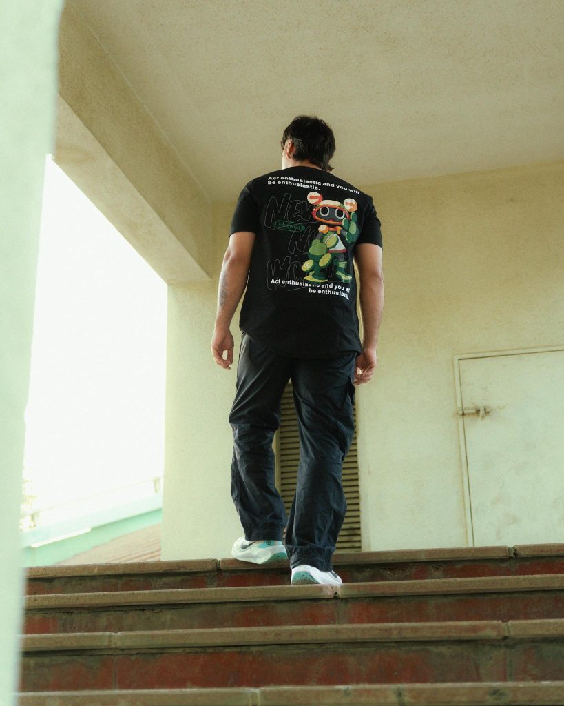 A man in a black t - shirt is walking down some stairs